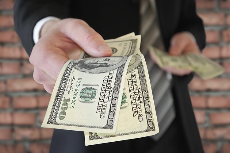  A man in a business suit offers money (© Shutterstock/Oleksandrum) 